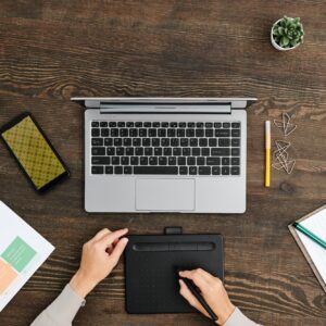 Overview of hands of young creative designer using stylus and graphic tablet